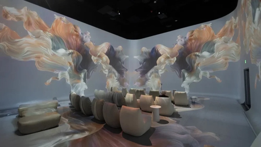 Projected swirling forms across the walls of an immersive room
